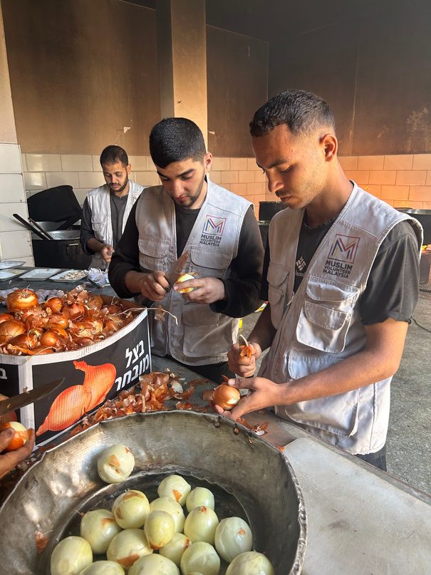 Petugas dapur menyediakan makanan dalam periuk besar
